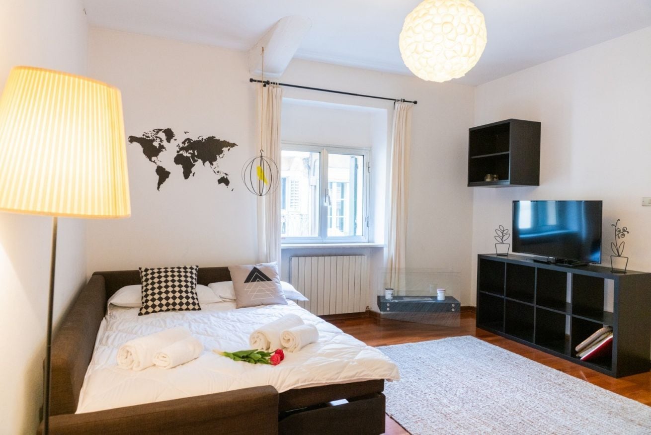 A modern bedroom with a large bed, a TV, and a world map on the wall.