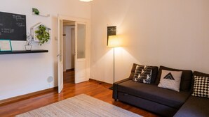 A cozy living room with a dark grey sofa, patterned cushions, a standing lamp, and a chalkboard with writing on the wall. - Cozy Residence Rocchetto - 25 meters from P. Erbe (Verona)