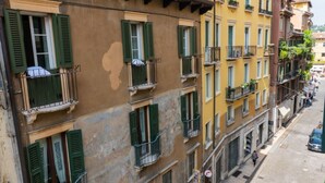 A multi-story building with balconies, a street view, and a pedestrian walkway. - Cozy Residence Rocchetto - 25 meters from P. Erbe (Verona)