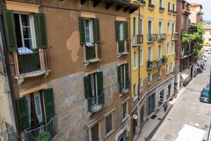 A multi-story building with balconies, a street view, and a pedestrian walkway. - Cozy Residence Rocchetto - 25 meters from P. Erbe (Verona)