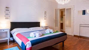 A neatly made bed with rolled towels, a bedside table, a nightstand, a hanging light fixture, and a wardrobe. - Cozy Residence Rocchetto - 25 meters from P. Erbe (Verona)