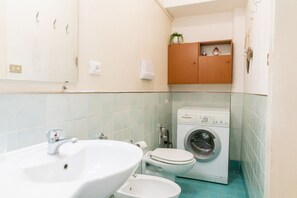 A compact bathroom with a sink, toilet, and washing machine. - Cozy Residence Rocchetto - 25 meters from P. Erbe (Verona)