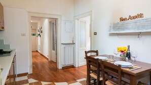 A dining area with a checkered floor, wooden chairs, a table set for two, and a wall-mounted sign reading "Bon Appetit". - Cozy Residence Rocchetto - 25 meters from P. Erbe (Verona)