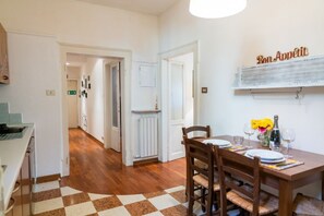 A dining area with a checkered floor, wooden chairs, a table set for two, and a wall-mounted sign reading "Bon Appetit". - Cozy Residence Rocchetto - 25 meters from P. Erbe (Verona)