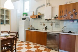 A kitchen with wooden cabinets, a stainless steel dishwasher, and a checkered floor.