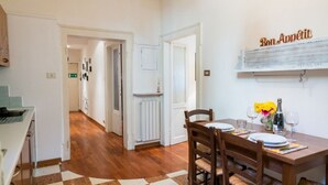 A dining area with a checkered floor, wooden chairs, a table set for two, and a wall-mounted sign reading "Bon Appetit". - Cozy Residence Rocchetto - 25 meters from P. Erbe (Verona)