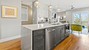 Uma cozinha moderna com bancada de mármore, eletrodomésticos de aço inoxidável e iluminação pendente.