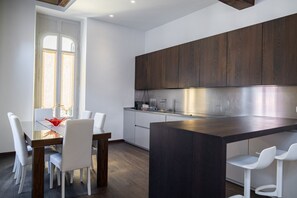 Una cocina moderna con armarios de madera oscura, una campana extractora de acero inoxidable y una isla central con taburetes de bar.