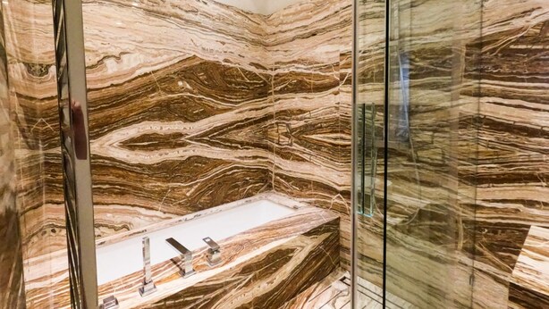 A bathroom with a large marble wall and a glass shower enclosure. - Majestic Mazzini Residence with 3 bedrooms and 3 bathrooms (Verona)