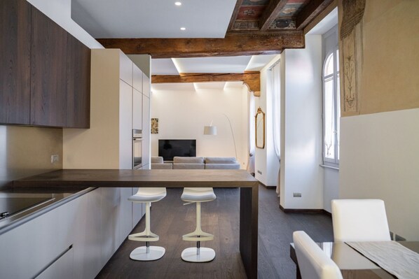 A modern kitchen with a central island, bar stools, and a dining area with a table and chairs.