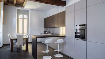 Eine moderne Küche mit weißen Schränken, einer dunklen Arbeitsplatte und einem eingebauten Backofen. Es gibt eine Essecke mit Tisch und Stühlen.
