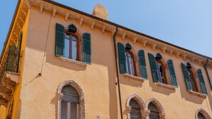 A building with arched windows and green shutters, featuring a classic architectural style. - Majestic Mazzini Residence with 3 bedrooms and 3 bathrooms (Verona)