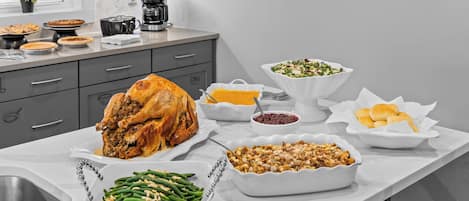 A kitchen counter with a roasted turkey, various side dishes, and a coffee maker.
