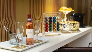 Una zona de bar con una botella de vino Zeni, copas y un recipiente de vidrio decorativo con adornos coloridos.