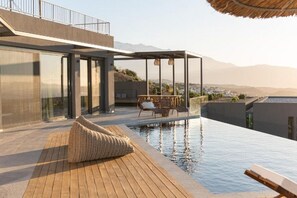 Ein moderner Pool auf dem Dach mit Glasumrandung, Holzterrasse und Sitzbereich.