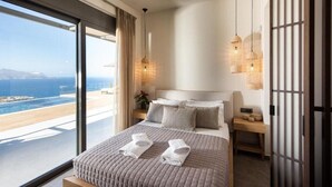 Una camera da letto moderna con un letto grande, vista sul mare e un balcone.