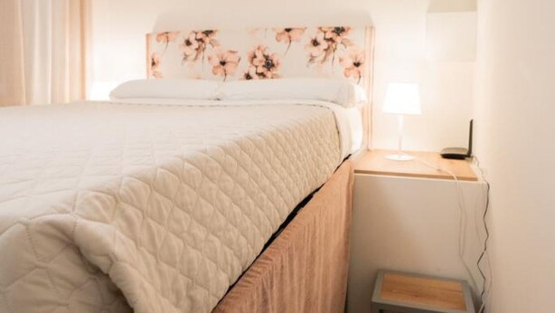 Un dormitorio con una cama, una mesita de noche y una lámpara.