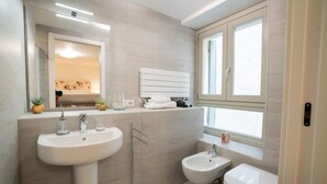 Un baño moderno con un lavamanos grande, un bidé y un inodoro, un espejo y una ventana que proporciona luz natural.