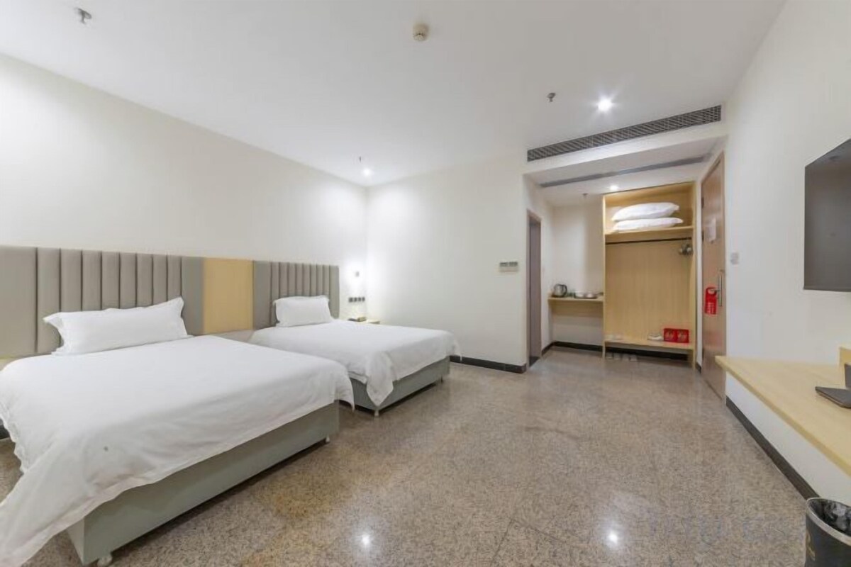 Habitación de hotel con dos camas, televisión, escritorio y baño.