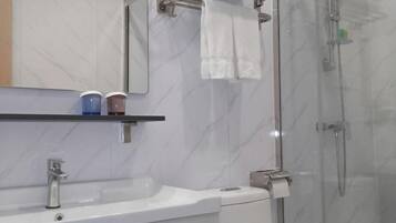 A modern bathroom with a white sink, mirror, and towel rack.