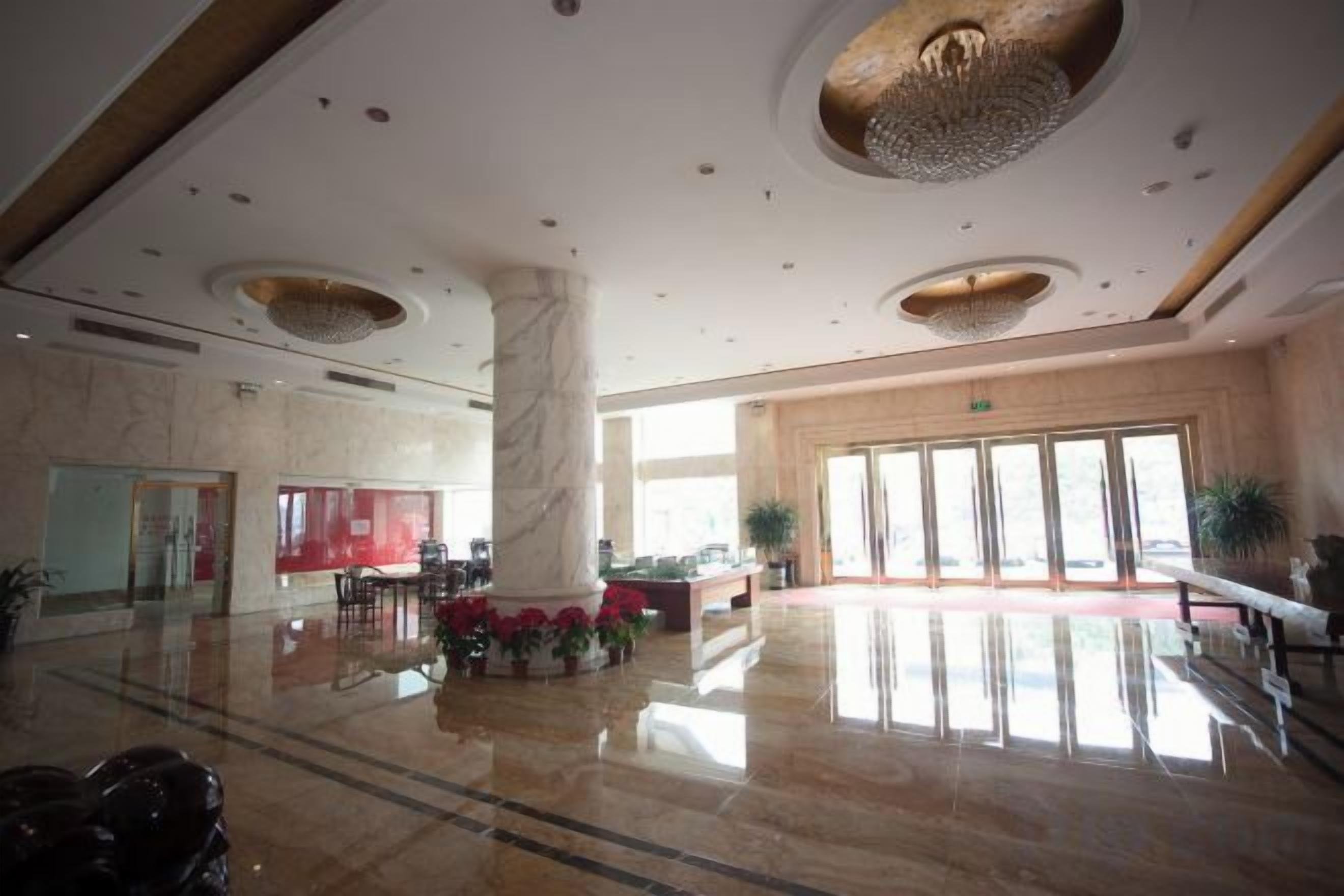 A spacious lobby with a marble floor, a central column, and a large window providing natural light.