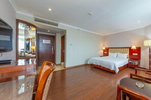 Una habitación de hotel con una cama, mesitas de noche, un escritorio y una silla.
