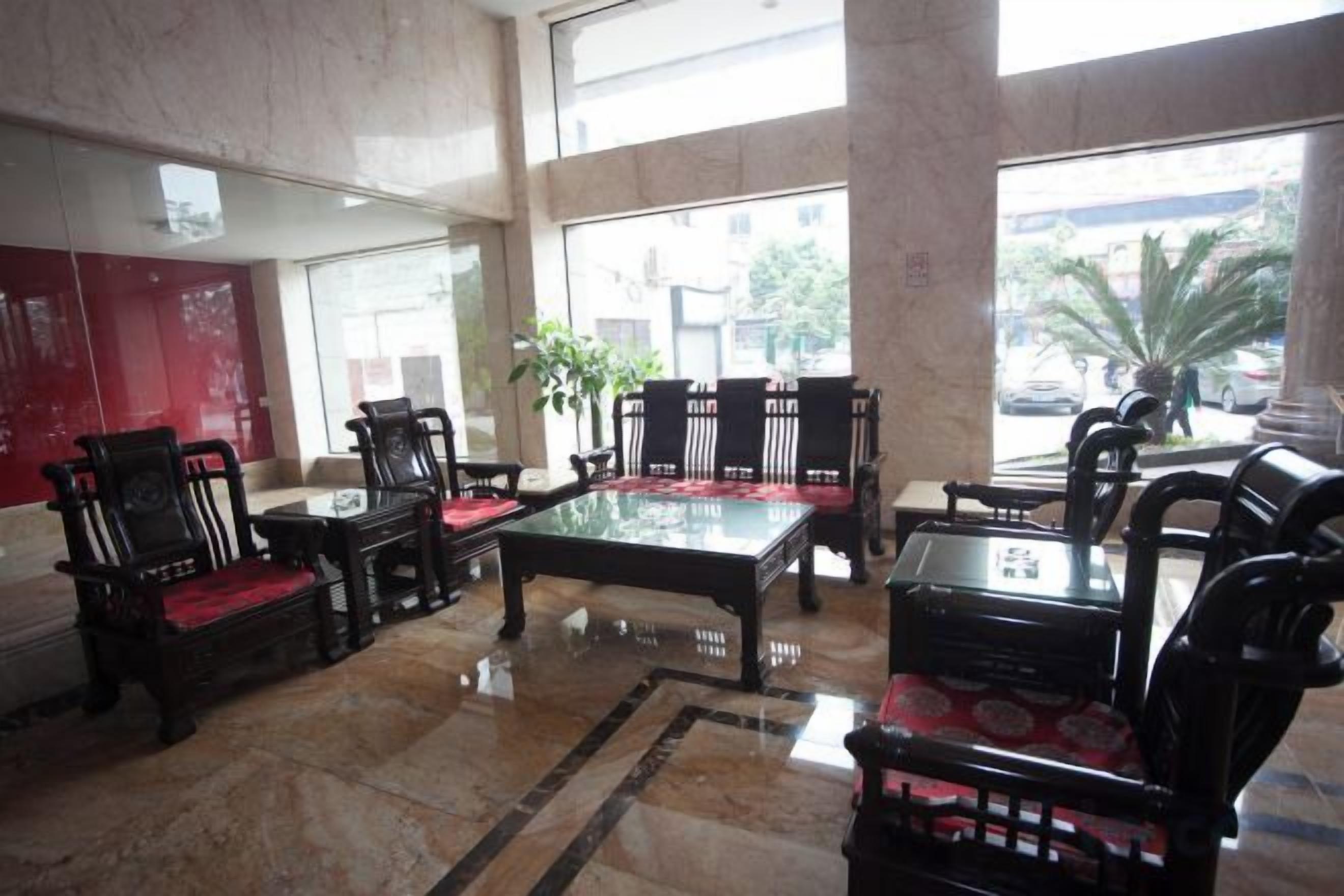Un hall d’entrée doté d’un sol en marbre, d’une cloison en verre et d’un espace détente avec des fauteuils et une table.