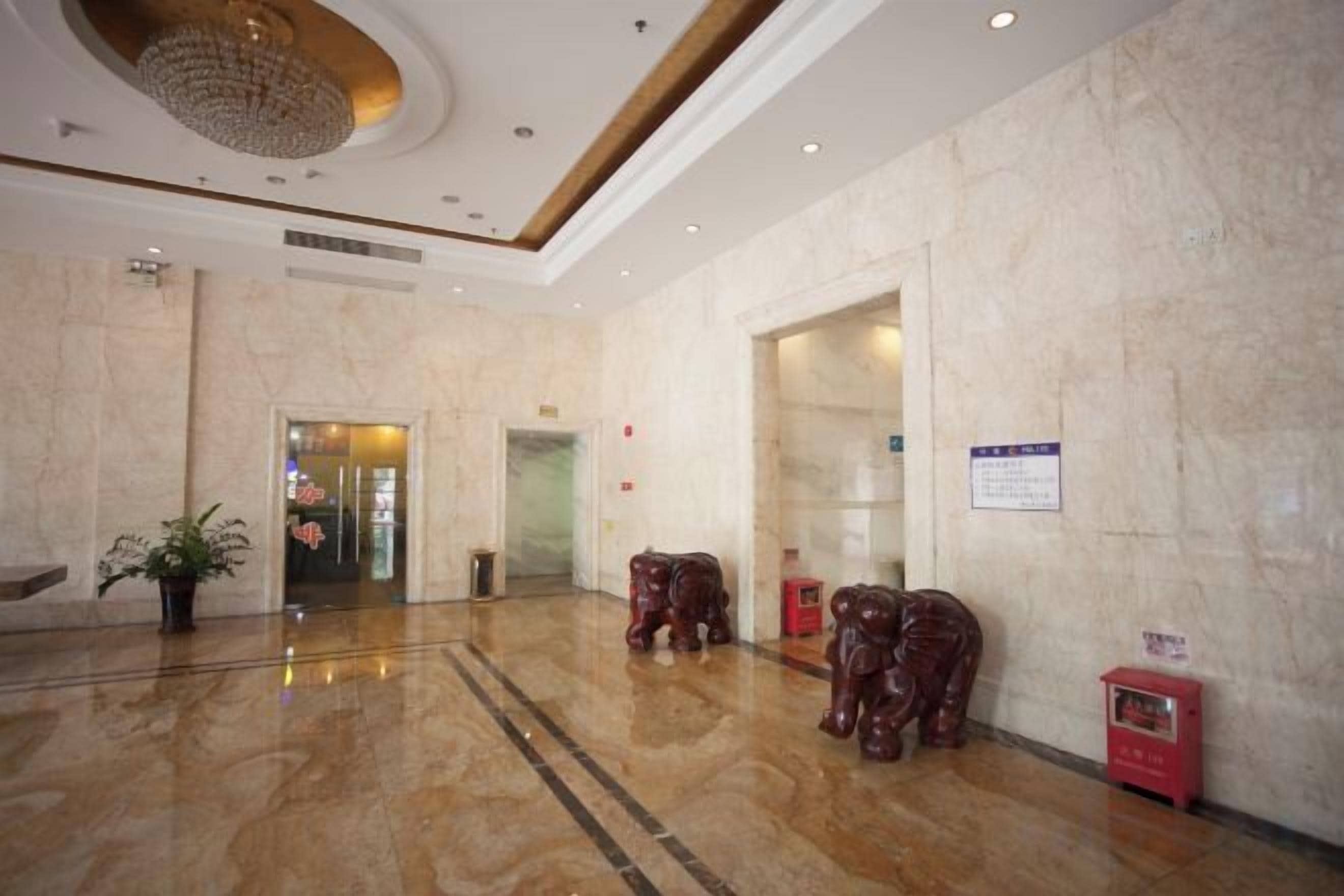 A lobby with marble flooring, a chandelier, and a reception desk.