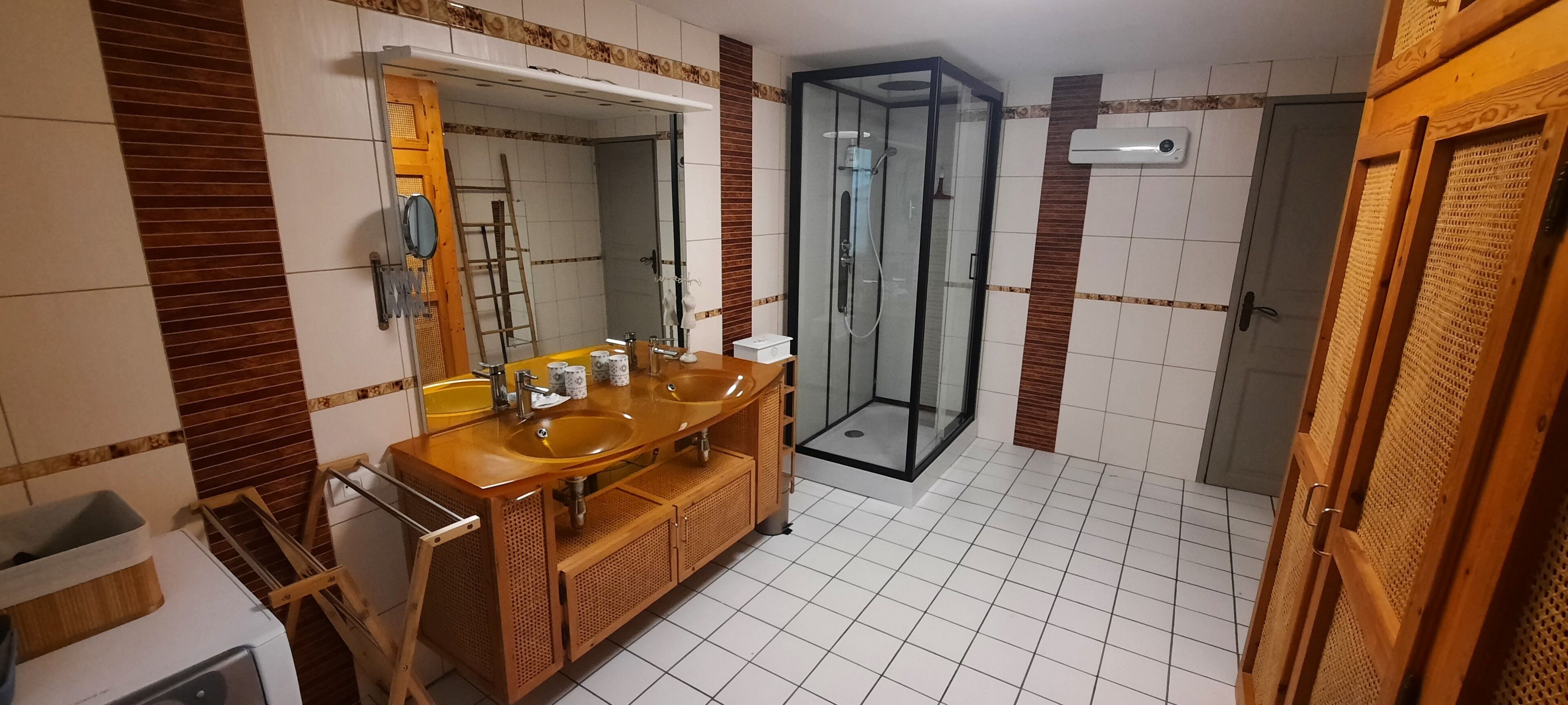 A bathroom with a wooden vanity, a glass shower enclosure, and a tiled floor.
