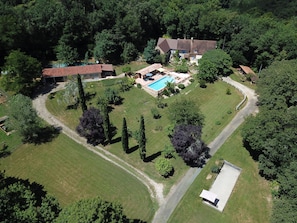 Luchtbeeld van een pand met een zwembad, een groot huis en een omheind erf.