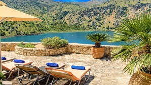 A terrace with lounge chairs and a view of a lake surrounded by hills. - Du Lac Villas 2 Private Pools (Kavallos)