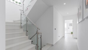 A modern staircase with glass railings and white walls.