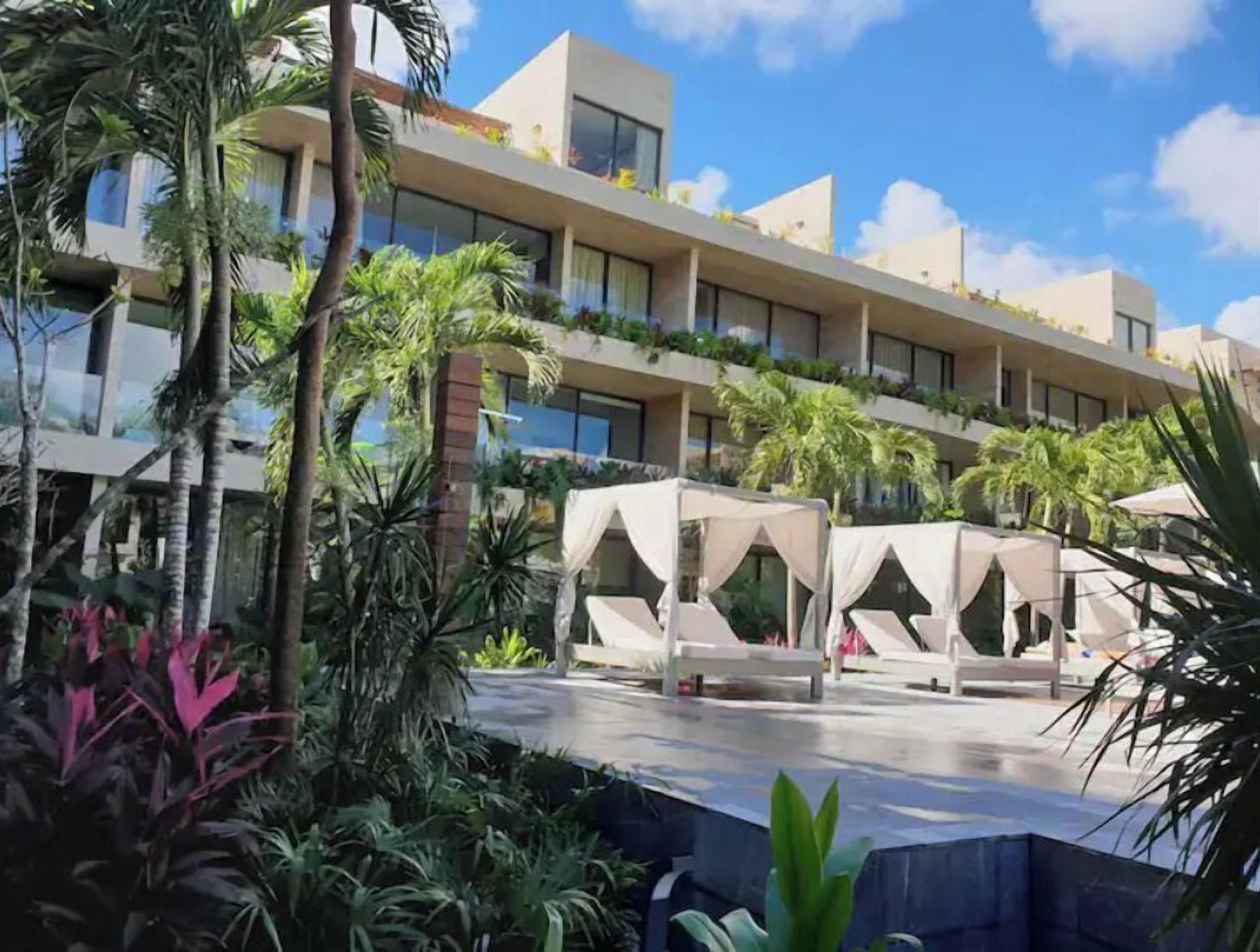 A hotel with multiple balconies, outdoor seating areas, and lush greenery.