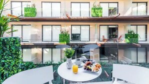 A modern outdoor dining area with a round table, a white vase, and a tray of food. - Wonderful studio in Menesse Condominium (Tulum)