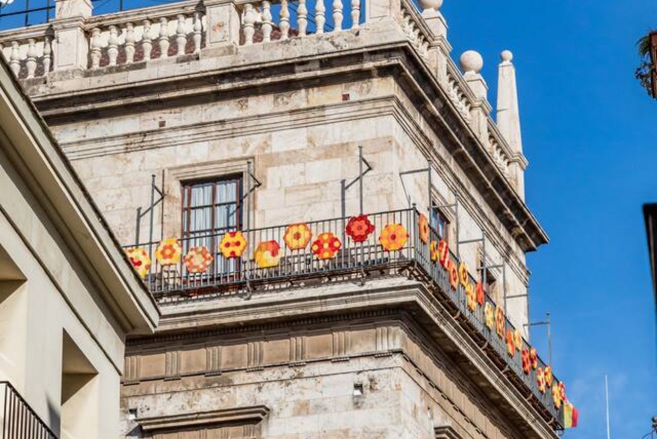 A building facade with a balcony adorned with colorful flower decorations.
