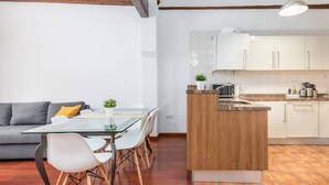 A modern kitchen with white cabinets, a wooden island, and a dining area with a glass table and white chairs.