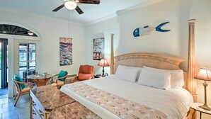 Een hotelkamer met een groot bed, een nachtkastje van marmer, een houten dressoir, een stoel, een lamp en kunst aan de muren.