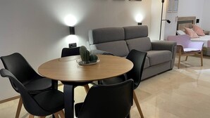 A modern living room with a grey sofa, black chairs, a round wooden table, and a cactus centerpiece.