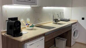 A compact kitchen with a coffee maker, sink, microwave, and washing machine.