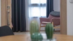 Una habitación con una mesa de madera, una silla y dos cactus sobre la mesa.