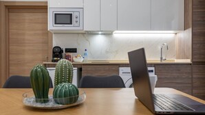 A modern kitchen with a microwave, coffee maker, and a laptop on the counter.