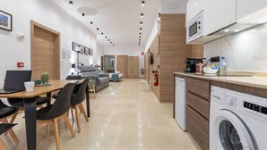 A modern kitchen with a microwave, sink, and washing machine. There is a dining area with a table and chairs.