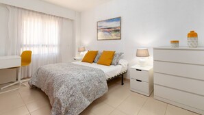 A bedroom with a bed, two bedside tables, a desk, and a chair. - Heliopolis with sea views. (Benicàssim)