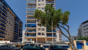 A multi-story building with balconies, a tree in front, and parked cars. - Heliopolis with sea views. (Benicàssim)