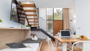 A modern hotel room with a wooden staircase, a bed, a desk with a laptop, and a breakfast setup. - Alameda suites loft 1. (Valencia / València)