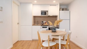 A modern kitchen with white cabinets, a microwave, a refrigerator, and a dining table with chairs. - Alameda suites loft 1. (Valencia / València)