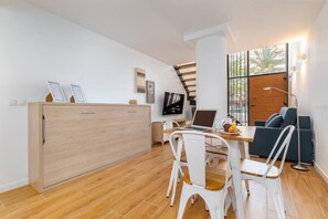 Una cocina moderna con un armario de madera, una mesa de comedor con sillas, una computadora portátil y un televisor.