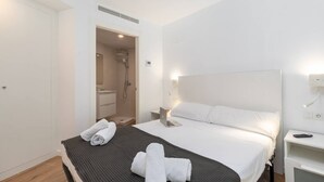 Een moderne hotelkamer met een groot bed, een nachtkastje met lamp, en een douche die zichtbaar is door een open deur.