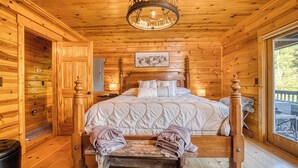 A wooden cabin bedroom with a bed, a bench, a rug, and a chandelier.