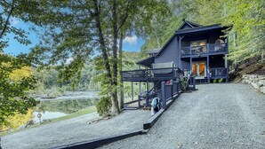 A cabin with a balcony, a gravel driveway, and a lake view.